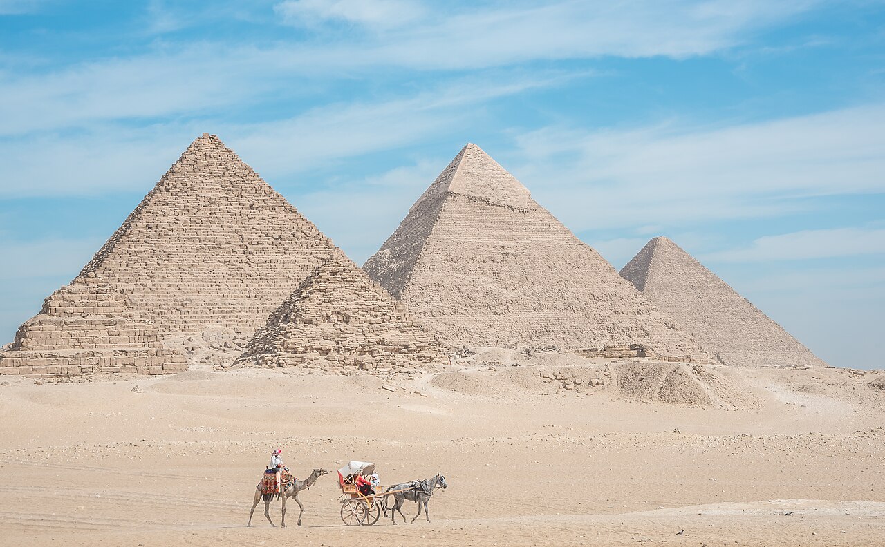 The pyramids of Giza with a camel rider and horse-drawn carriage in the foreground